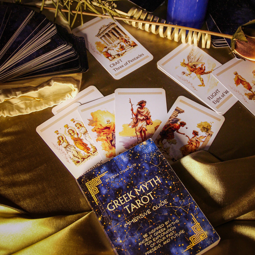 Greek Myth Tarot cards with a blue candle and feathers on a dark surface