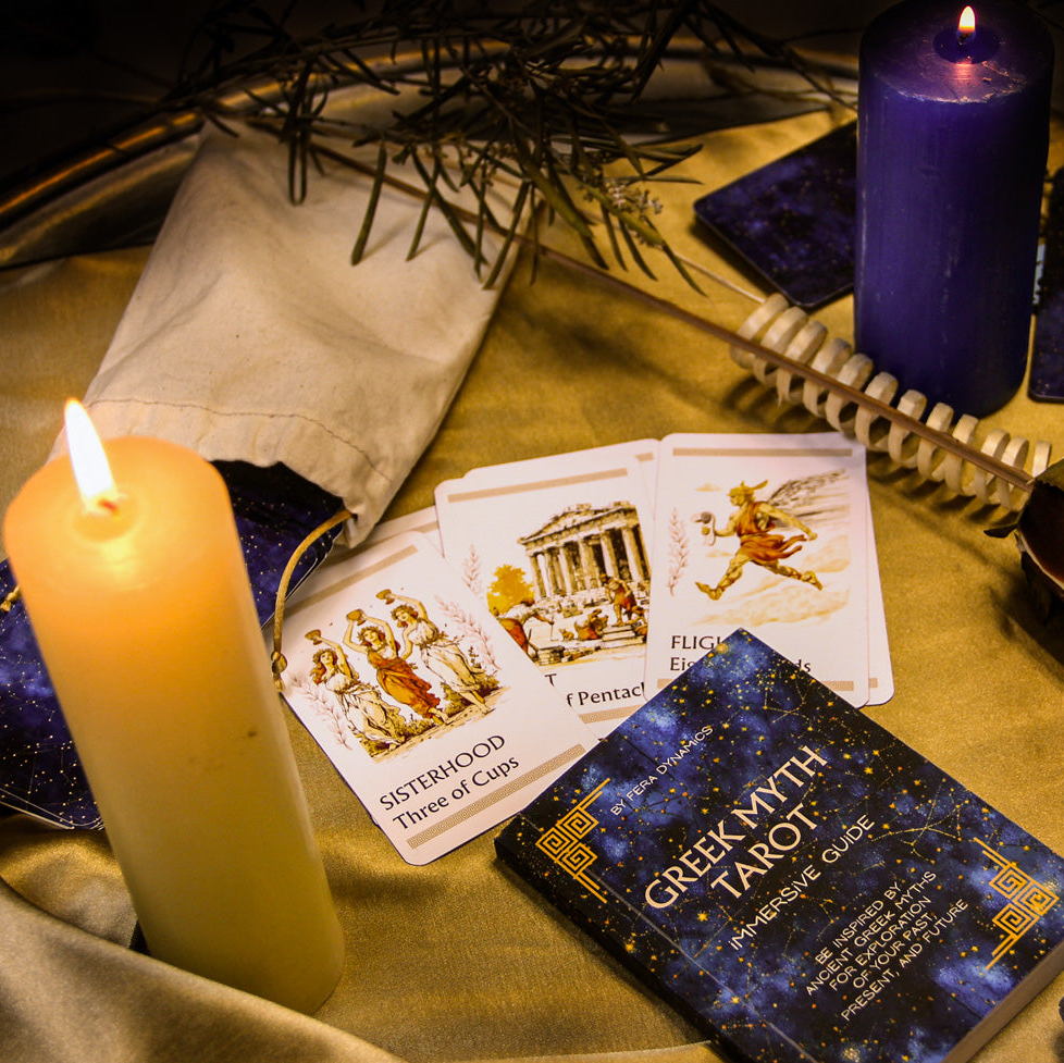 Tarot cards, candles, and a book on a table with a mystical atmosphere.
